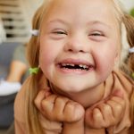 Cuidado bucal en niños con síndrome de down. Retrato de una chica rubia con síndrome de down sonriendo alegremente mirando a la cámara